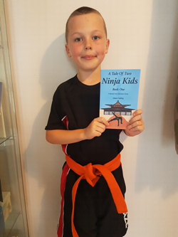 Young ninja holding "A Tale Of Two Ninja Kids" book. Young ninja holding "A Tale Of Two Ninja Kids" book.